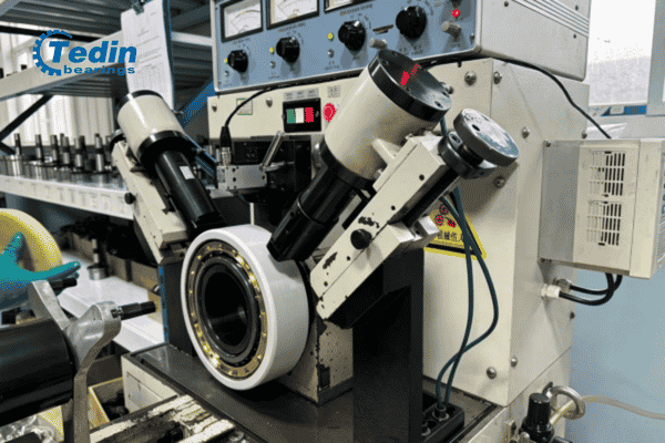 Quality inspector conducting 100% batch-level vibration and noise testing on cylindrical roller bearings.
